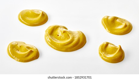 five assorted decorative twists of yellow mustard isolated on white with copyspace below