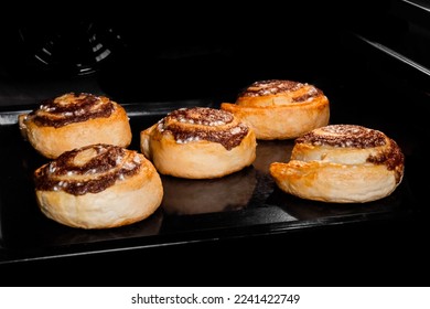 Five baked cinnamon buns on tray in electric oven. Swedish cuisine, homemade bakery, food, cooking and pastry concept