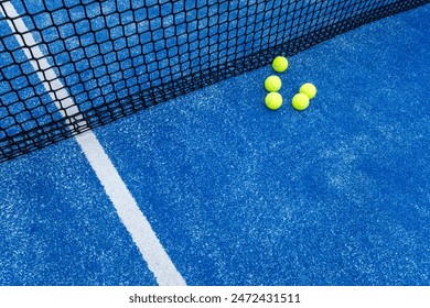 five balls next to the net of a blue paddle tennis court - Powered by Shutterstock