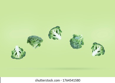 Five broccoli soar freely on a green background with slight shadow. Creative flying food concept. Minimalist vegetable banner with copy space for text.