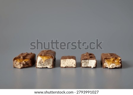 Five broken chocolate bars with different visible fillings isolated on a gray background, showcasing confectionery variety, textures, and product selection concepts