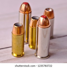 Five bullets, two 44 special and three 40 caliber hollow points on a white wooden back ground