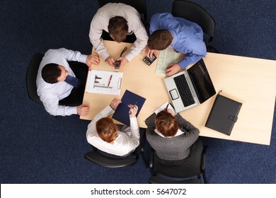 Five Business People Meeting - Businesspeople Gathered Around A Table For A Meeting, Brainstorming. Aerial Shot Taken From Directly Above The Table.