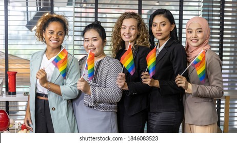 Five Business Women From Different Ethnic Races And Cultures Express Support For LGBT With Flags In An Office