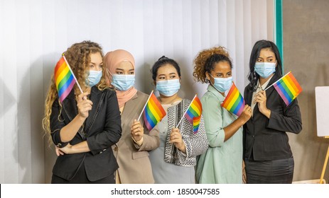 Five Business Women From Different Ethnic Races And Cultures With Protective Mask Express Support For LGBT With Flags In An Office