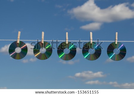 Five CDs on a clothesline attached with wooden clothespins.