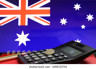 Five cents coin of Australia on the calculator with pencils on the red floor and blue color of Australian nation flag background, the concept of finance.