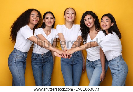 Five Cheerful Diverse Women Holding Hands Standing On Yellow Studio Background, Smiling To Camera. Female Unity And Friendship, Togetherness And Teamwork Concept