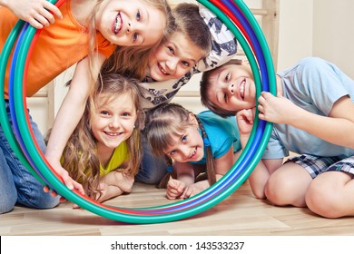 Fünf fröhliche Kinder, die durch Hula-Hoops schauen
