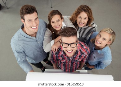 Five Cheerful Young Workmates Smiling At The Camera From High Angle View Inside The Office.