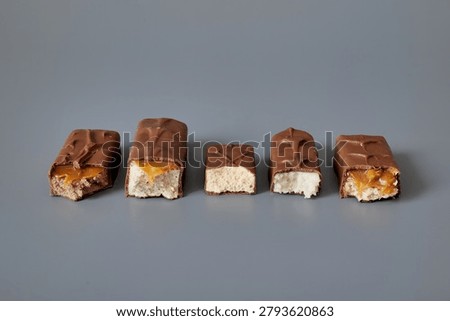 Five chocolate bars with different fillings isolated on a gray background, showcasing product variety, confectionery textures, and sweet snack assortment