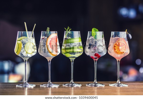 ポップやレストランのバーカウンターに ワイングラスをかけたカラフルな5つのジントニックカクテル の写真素材 今すぐ編集