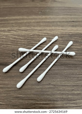 Five cotton tips sitting on a dark brown, oak background in a random, unnatural pattern