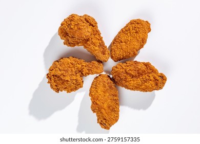 Five crispy deep-fried chicken wings arranged in a circle on whi