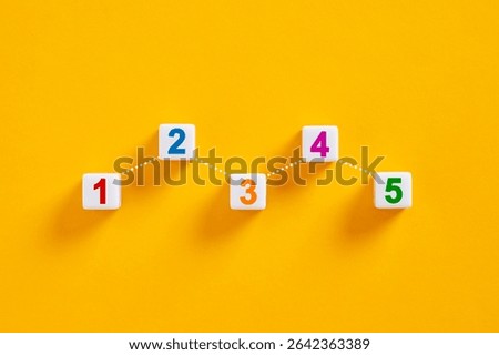 Five cubes showing an increasing trend from one to five on a yellow background, representing the steps of growth and progress.