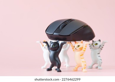 Five cute toy kittens carry a gray computer mouse in their raised paws. A playful concept about loot and choosing the best computer mouse. Toy world. Copy space. Selective focus. Close-up