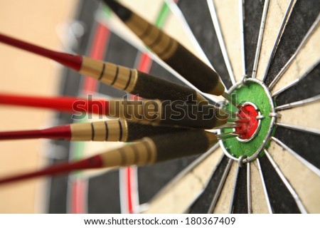 Five darts hitting bullseye on dartboard 