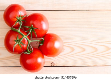 Five deep red ripe medium tomatoes over unfinished wooden planks. Includes copy space.