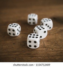 Five dices on an old rustic wooden table showing the number six. Narrow depth of field.