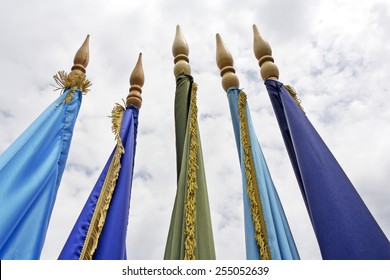 Five different colored flags on the flagpole, the clouds in the background 