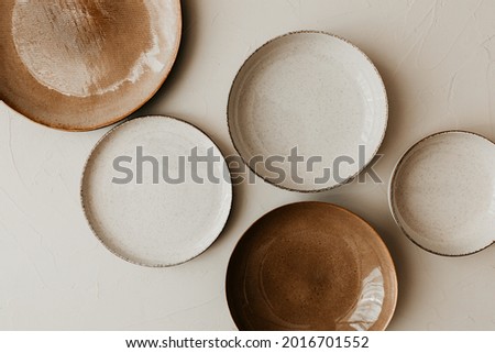 Five different size plate on beige background. Flat lay, top view. Brown and natural color plates. Textured grainy pattern on the plates.