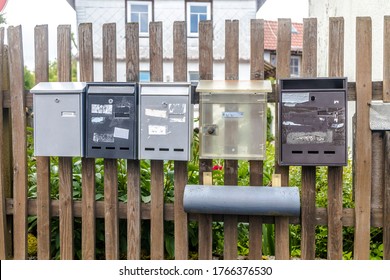 Five dirty and weathered Mail Boxes hanging on a wooden Fence