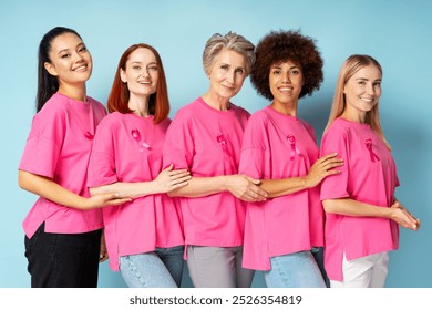 Five diverse women of different ages and ethnicities are standing together, wearing pink t shirts with pink ribbons, symbolizing their unity and support for breast cancer awareness - Powered by Shutterstock