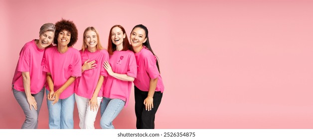 Five diverse women of different ages and ethnicities are laughing and posing together on a pink background, wearing pink shirts with pink ribbons - Powered by Shutterstock