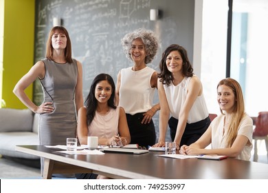 Five female colleagues at a work meeting smiling to camera