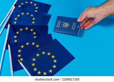 five flags of the eu and a hand holding out a passport of ukraine, the concept of joining the european union, copy space