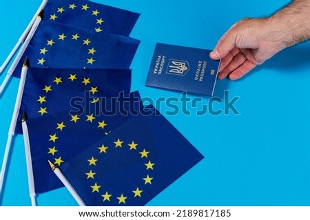 five flags of the eu and a hand holding out a passport of ukraine, the concept of joining the european union, copy space