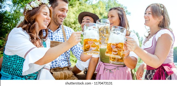 Five friends having fun on Bavarian RIver and clinking glasses with beer
