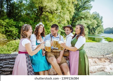 Five friends having fun on Bavarian RIver and clinking glasses with Oktoberfest 