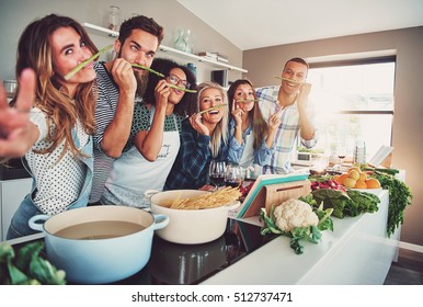 Five friends having a little break to fool around with some asparagus while cooking - Powered by Shutterstock