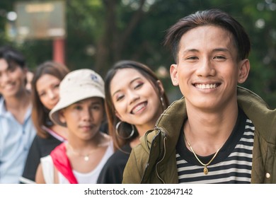 Five friends posing and smiling while in a single file. Focused on the young man on the right. - Powered by Shutterstock