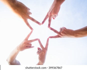 Five friends uniting their hands to make a star