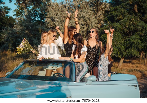 Five girls\
have fun on the car in the\
countryside