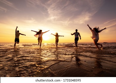 Five happy friends runs with raised arms at sunset beach - Powered by Shutterstock