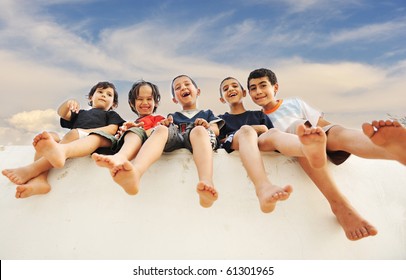 Five happy friends sitting on wall outdoor - Powered by Shutterstock