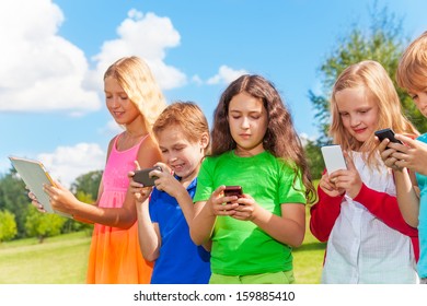 Five Happy Kids Stnading With Phones And Digital Devices