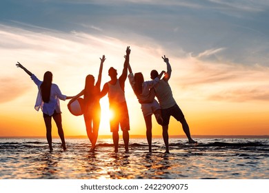 Five happy young friends are having fun, standing together, hugging and meeting sunset with open arms at calm sunset lake beach - Powered by Shutterstock