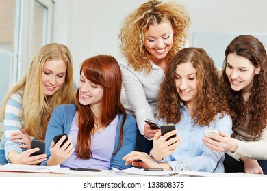 Five Happy Young Women Comparing Different Smartphones In College Class