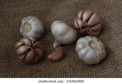 Five heads of garlic and a clove of garlic lie on a burlap. - Shutterstock ID 1763463905