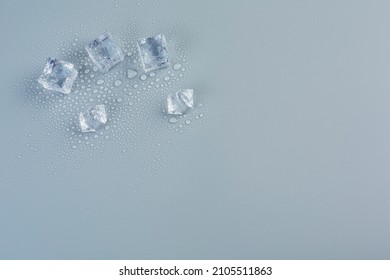 Five ice cubes in melted water on a gray background