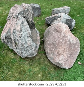 Five large boulder rocks in a grass field