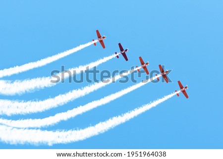 Five light engine airplane perform aerobatics in a cloud of smoke