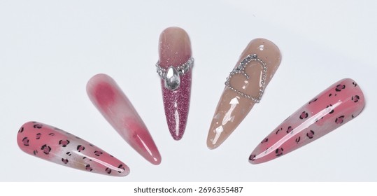 Five long unique artificial stiletto nails showcasing a blend of glamorous pink leopard pattern and elegant silver heart jewel accents