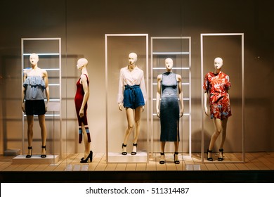 Five Mannequins Standing In Store Window Display Of Women's Casual Clothing Shop In Shopping Mall.