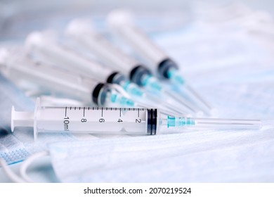 Five medical syringes are on the table. Disposable syringes and medical masks. Consumables for injection and virus protection. Horizontal photo. 