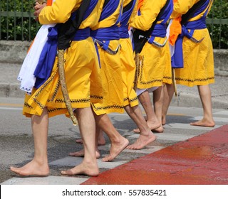 Five men of Sikh Religion with long dresses walking barefoot through the streets of the city during the event